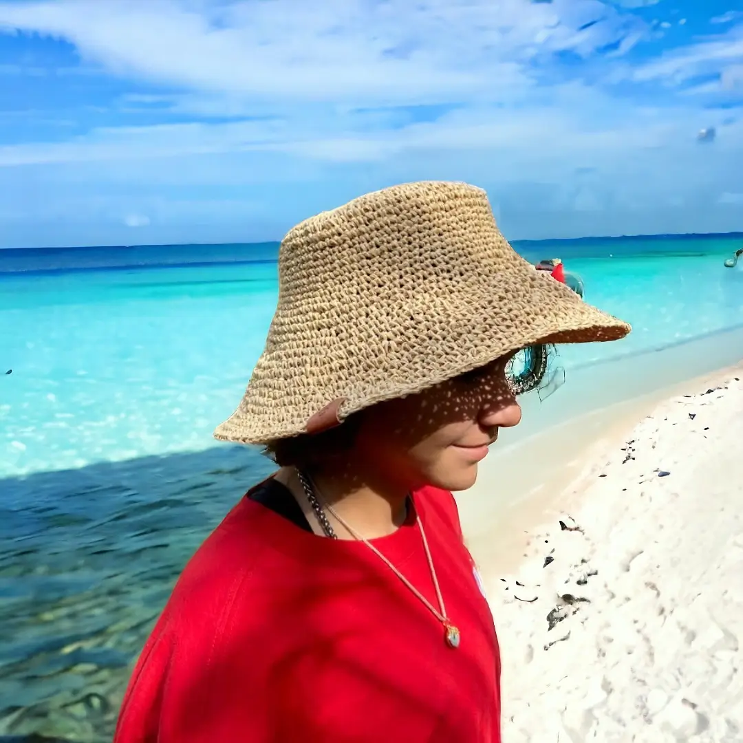 mes-crations-crochellem-galerieweb (21) Chapeau de paille à large bord porté par Marine devant une plage aux eaux turquoise.