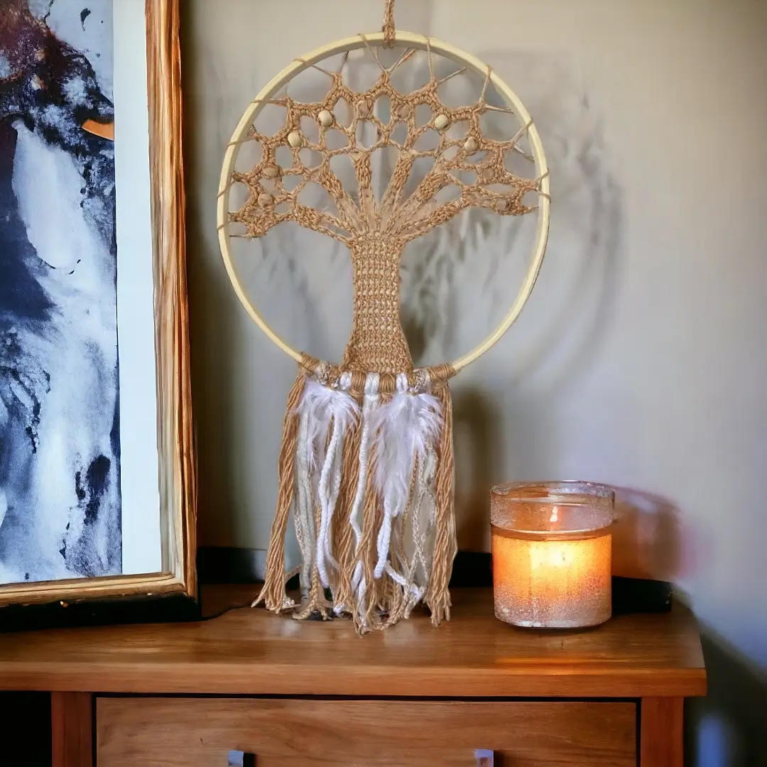 mes-crations-crochellem-galerieweb (32) Attrape-rêves en crochet avec motif d'arbre de vie et franges crème, accroché à côté d'un tableau et près d'une bougie allumée sur une commode en bois