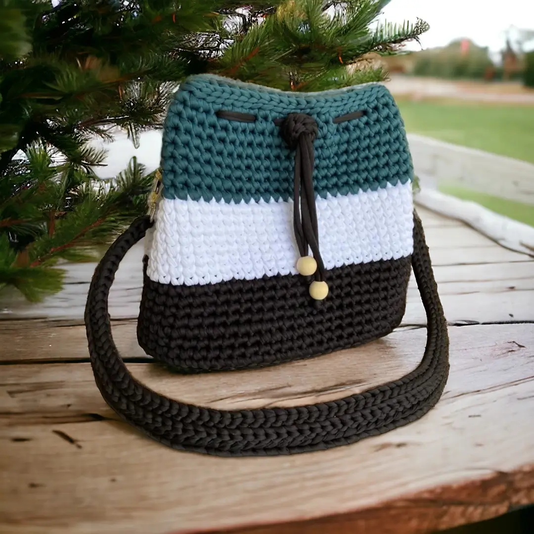 mes-crations-crochellem-galerieweb (4) Sac à bandoulière tricolore en crochet avec cordon et perles, posé sur une table en bois extérieure.