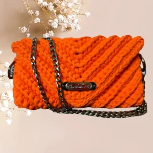 Pochette en crochet orange vif avec une bandoulière en chaîne métallique noir, un accessoire éclatant pour rehausser toute tenue, vue de face