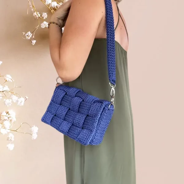 Sac à bandoulière en crochet bleu nuit avec un motif tressé, porté à l'épaule par mannequin