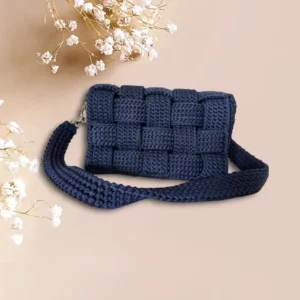 Sac à bandoulière en crochet bleu nuit avec un motif tressé.