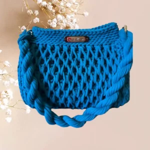 Sac bleu vibrant en crochet avec un motif en nid d'abeille et des anses torsadées, mêlant fonctionnalité et style artisanal, vue de face