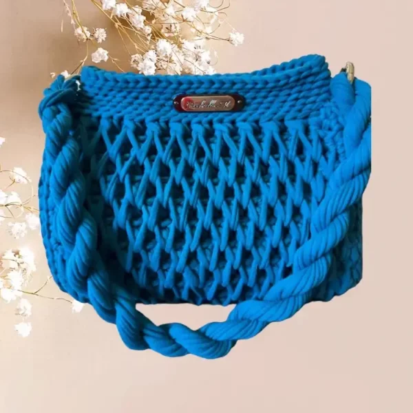 Sac bleu vibrant en crochet avec un motif en nid d'abeille et des anses torsadées, mêlant fonctionnalité et style artisanal, vue de face