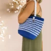 Sac cabas en crochet bleu marine et blanc avec anses torsadées, porté à l'épaule par mannequin