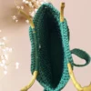 Sac à main en crochet vert émeraude avec anse en bambou et pendentif décoratif, vue de dessus