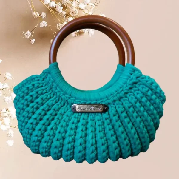 Panier à main crocheté en coton couleur bleu canard avec poignées rondes en bois marron, doté d'une plaque métallique portant l'inscription 'Crochellem vue de face