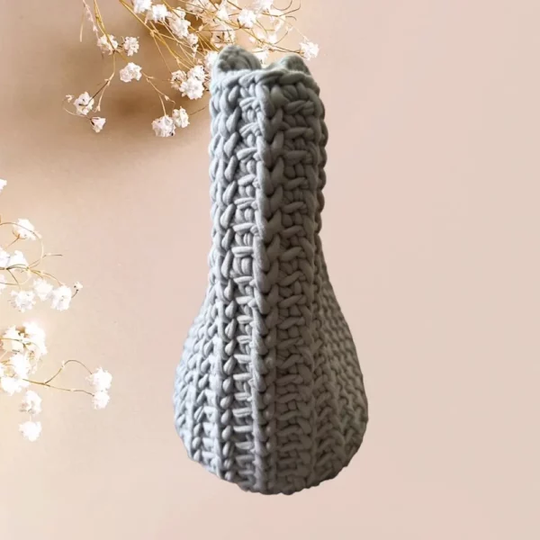 Un sac panier en crochet de couleur gris clair, orné d'une fermeture métallique vintage argenté, combine esthétique traditionnelle et praticité moderne, vue de profil