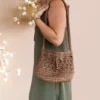 Sac seau en crochet marron avec cordon et perles de bois sur fond rose pâle, porté par mannequin